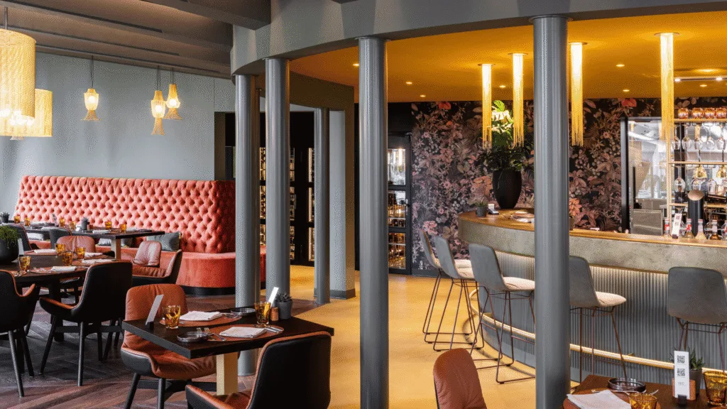 Layered lighting in a hospitality interior with willowlamp chandeliers and pendants, ambient lighting and task-oriented fixtures.